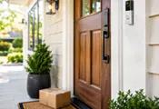 Smart video doorbell mounted beside a front door with a package on the porch, showing how a doorbell camera can monitor visitors and deliveries.